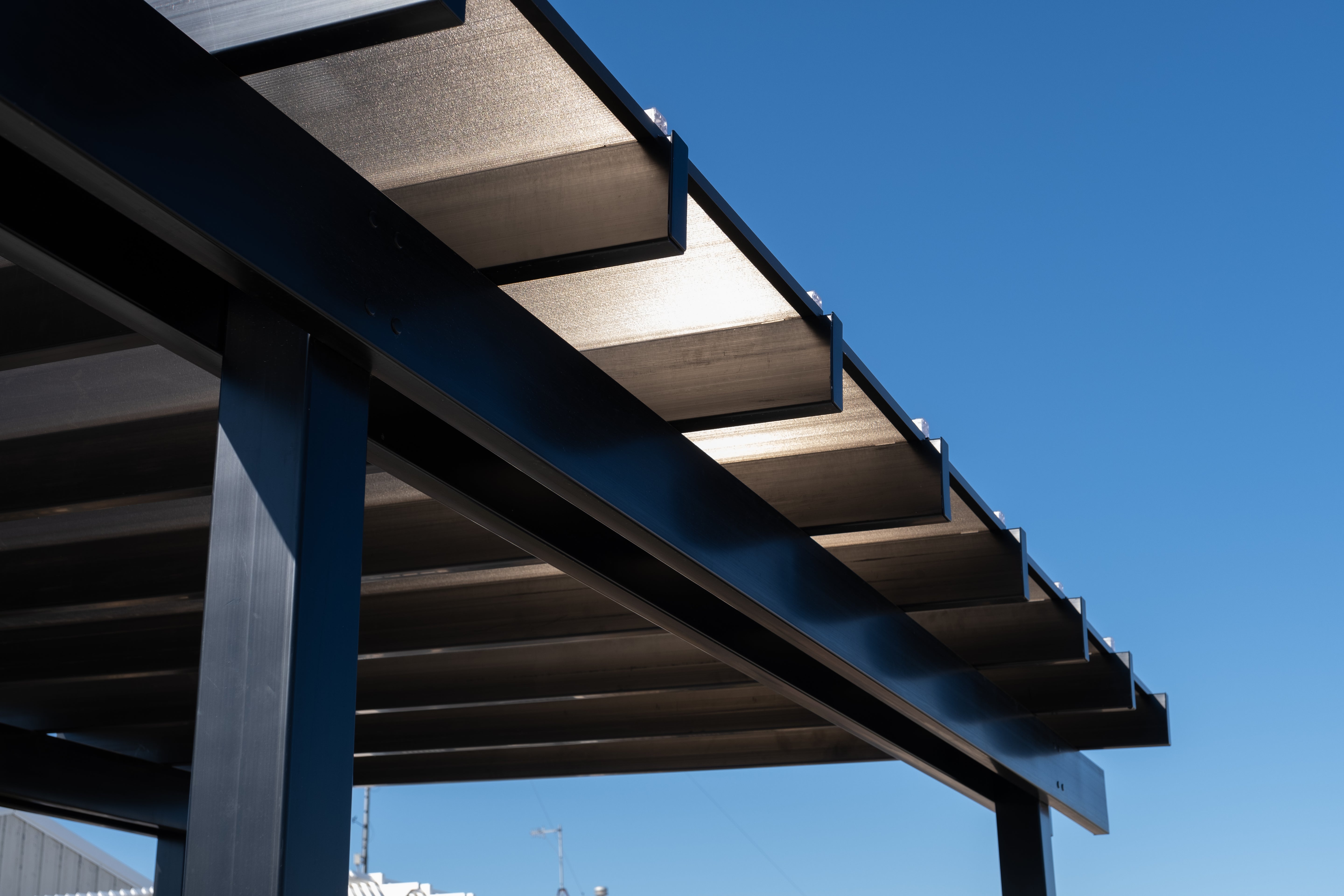 Moda Pergolas covered rainproof pergola structure against a clear blue sky
