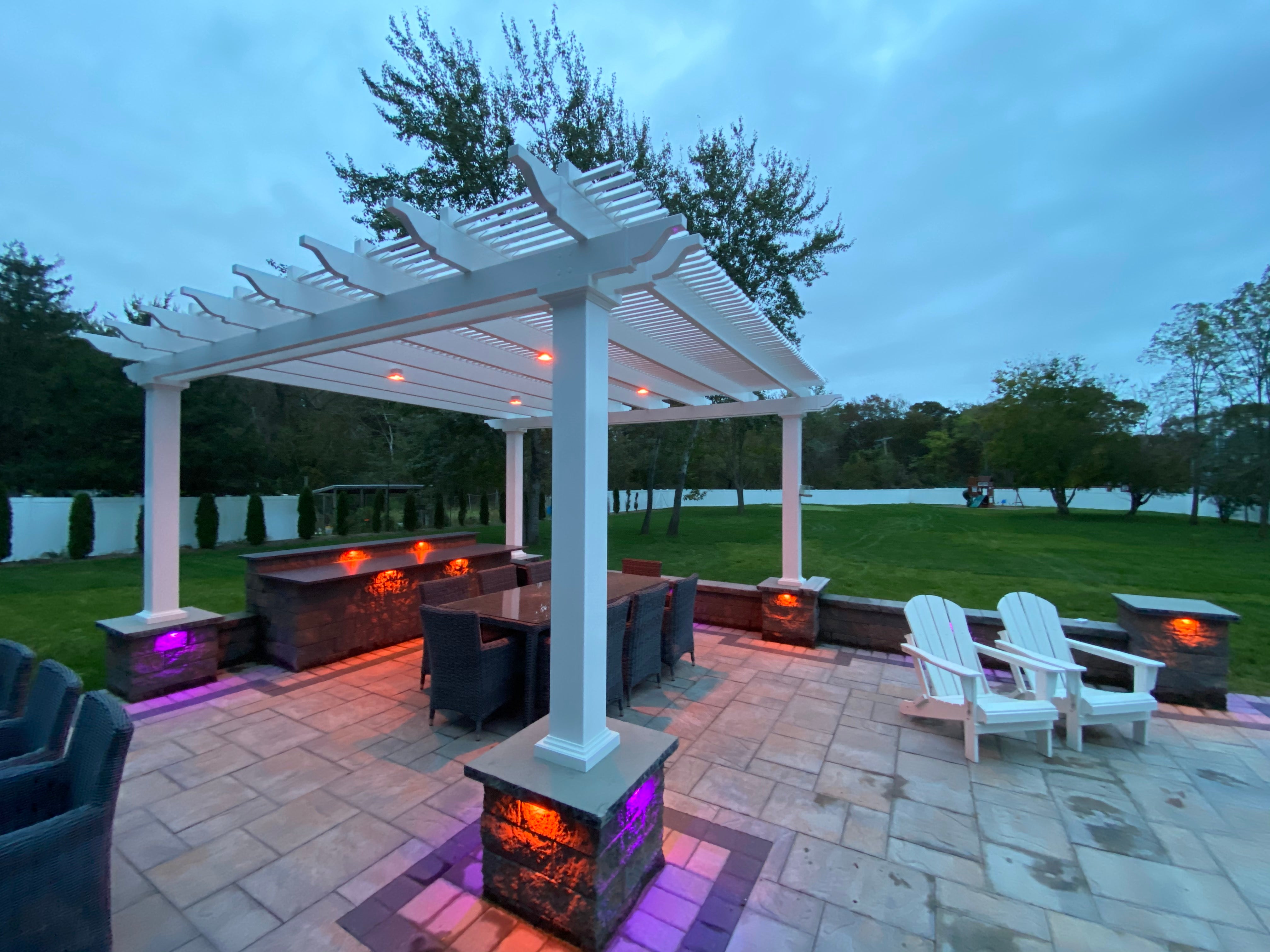 Outdoor patio with a Traditional Pergola by Moda Pergolas, fire pits, and chairs near a body of water.