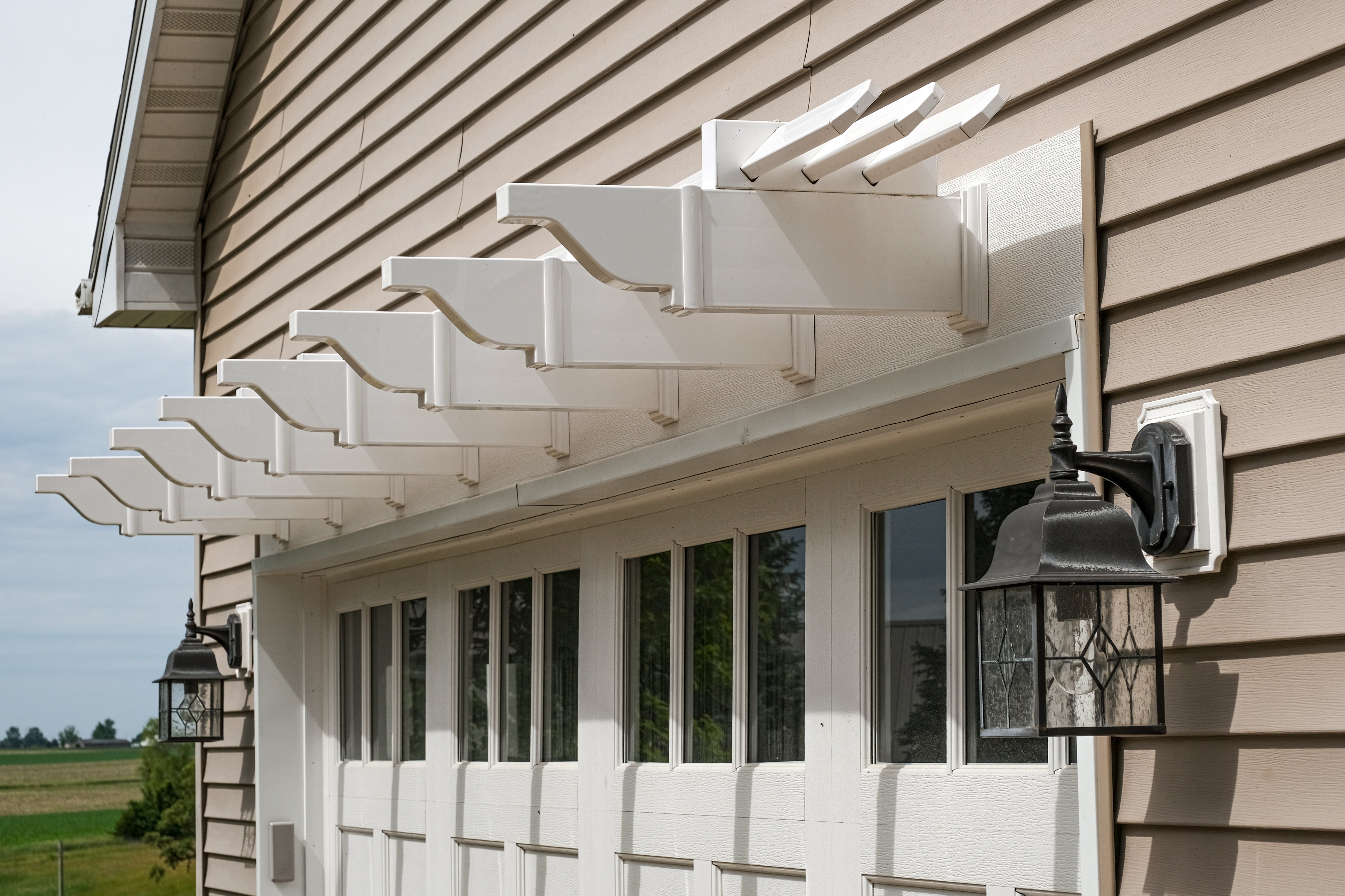 White decorative visor pergola on a house exterior with a clear sky background