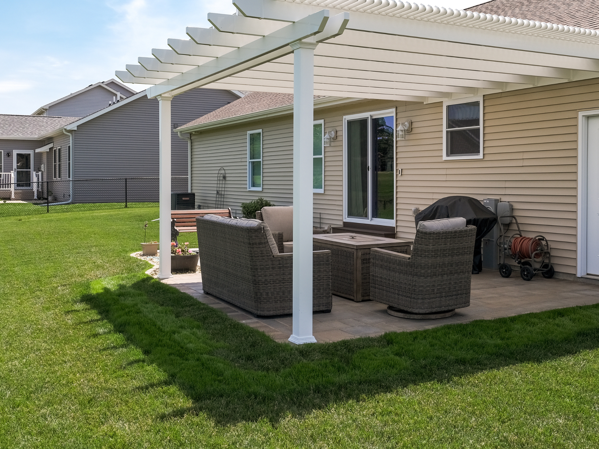 Outdoor patio with traditional pergola kit, furniture, and a house in the background