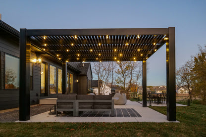 Outdoor patio with freestanding modern pergola and seating area at dusk