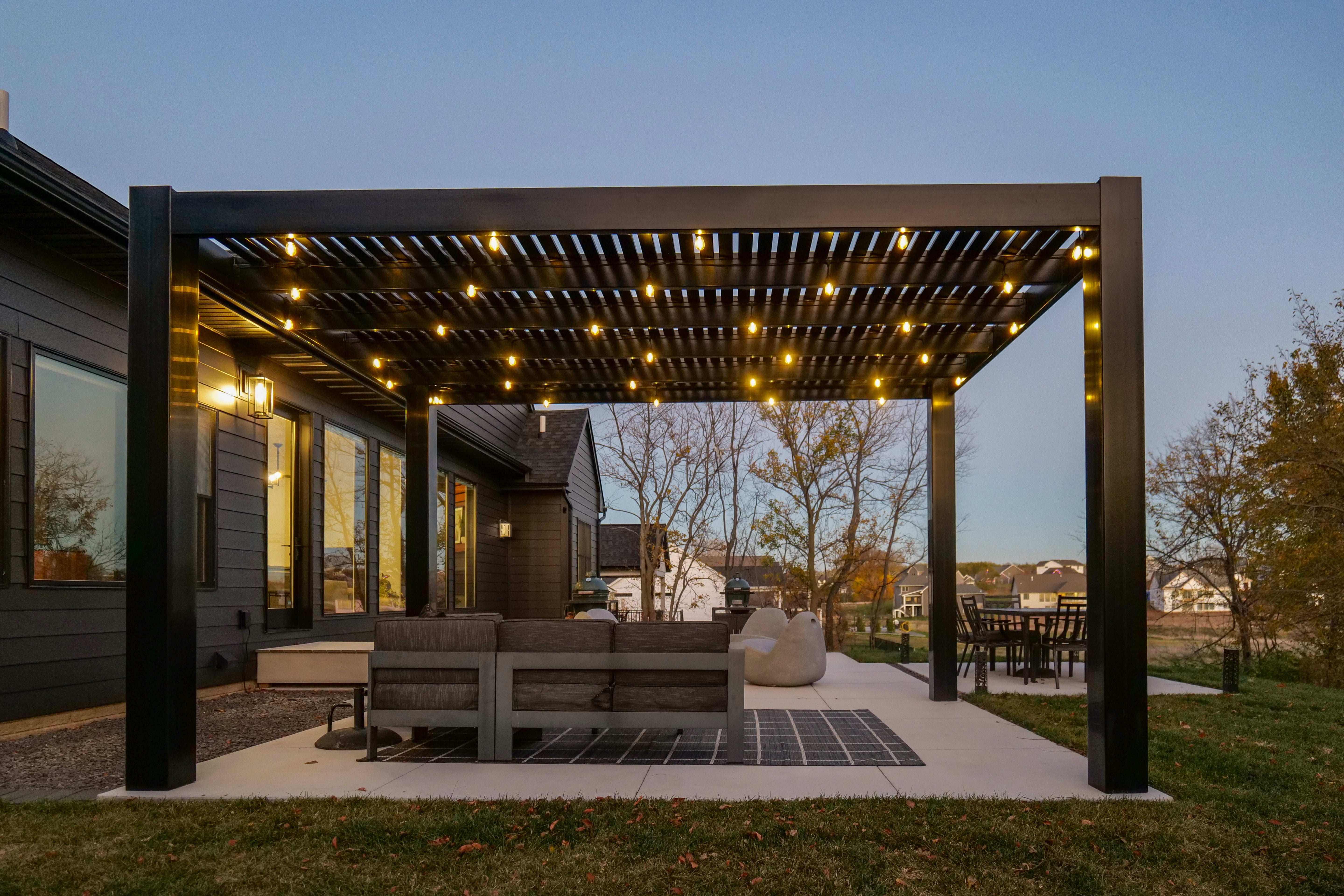 Outdoor patio with freestanding modern pergola and seating area at dusk